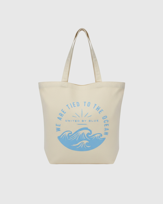 We Are Tied To The Ocean My Favorite Daily Tote (Front): Cream canvas tote with blue ocean waves and arched text graphic