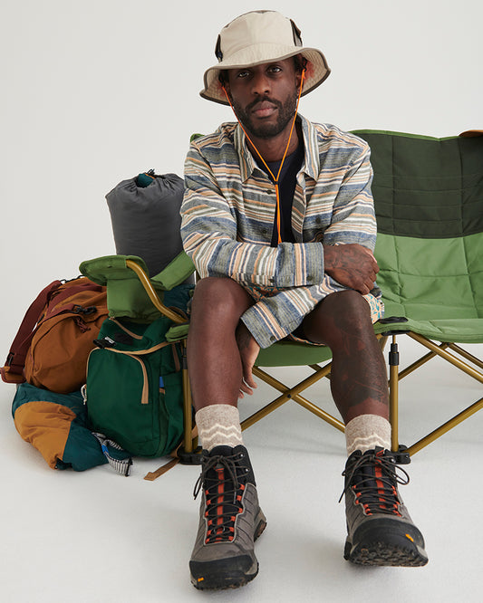 NATURAL / KHAKI UTILITY BUCKET HAT (In-use): Man wearing khaki bucket hat seated on green camping chair outdoors