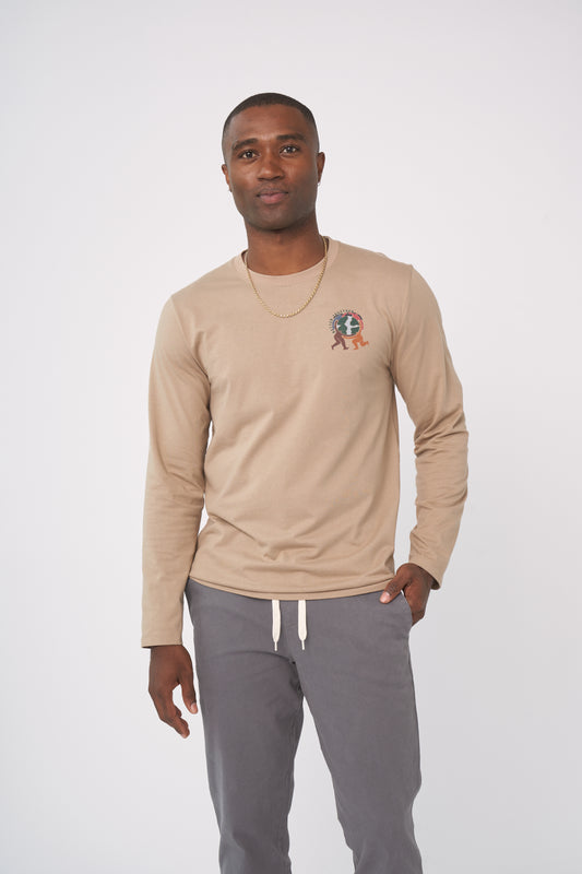 Ash Earth Circle - Long-Sleeve Graphic Tee (In-use): Man wearing tan long-sleeve tee with small globe graphic on chest