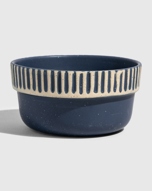Slate Stoneware Stackable Bowl (Angle): Round navy blue ceramic bowl with cream ribbed stripe near rim