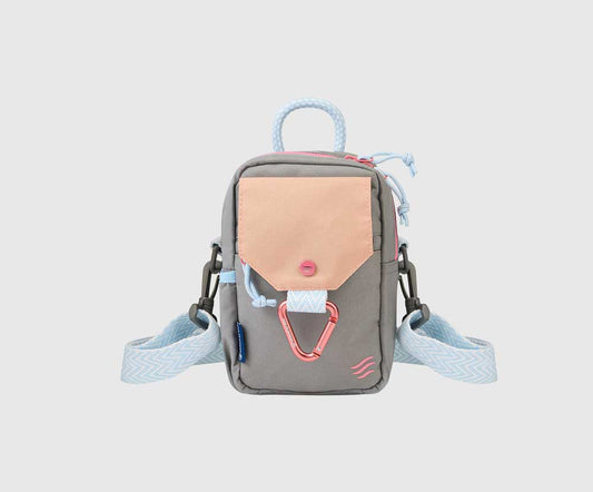Lt Grey (R)evolution™ Daily Cross Body (Front): Grey crossbody bag with peach pocket flap, pink carabiner, and light blue strap