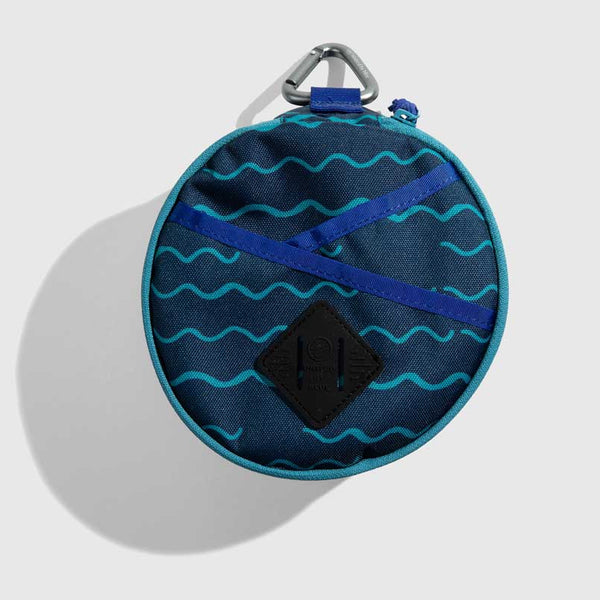 Navy The Meal Kit (Single) (Front): Round navy pouch with teal wave print, blue cross straps, carabiner clip