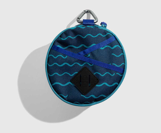 Navy The Meal Kit (Single) (Front): Round navy pouch with teal wave print, crossed blue straps, carabiner clip