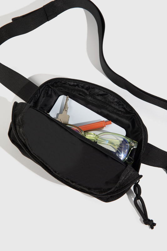 Black (Re)volution™ 1L Go-Anywhere Bag (Detail): Black fanny pack open, showing glasses, keys, card, and pen inside
