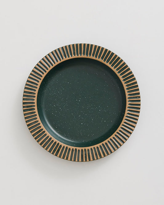 Pine Stoneware Stackable Plate (Flat-lay): Round dark green speckled plate with carved tan ribbed border pattern
