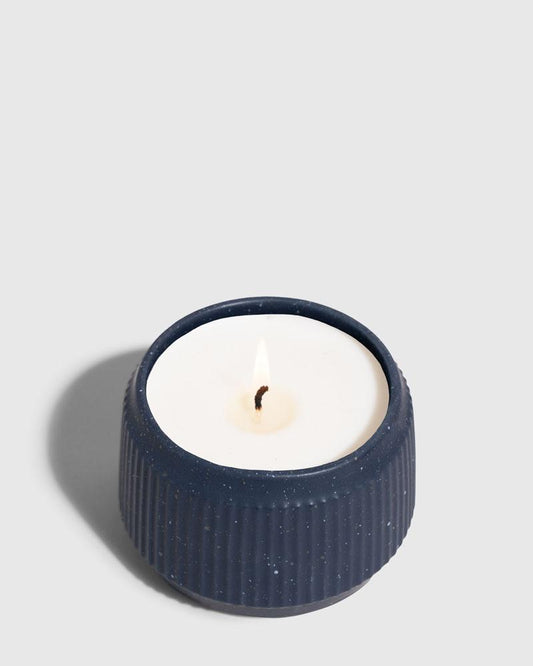 INDIGO 14 oz. Ceramic Keepsake Candle - Surf (Angle): Short navy ridged ceramic vessel holds white wax with lit wick
