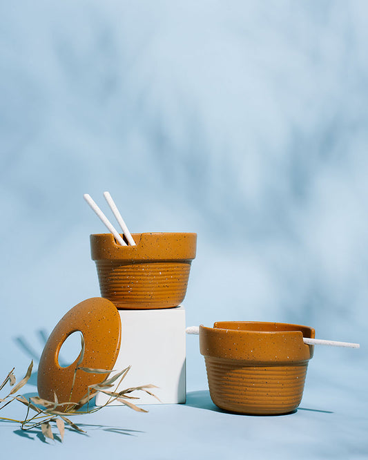 Caramel Stoneware Stackable Noodle Bowl Set (Angle): Two speckled amber bowls with ribbed bases, white chopsticks, and donut lid