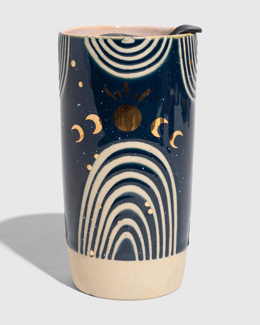 Nightfall Blue 10 oz. Insulated Stoneware Travel Mug (Angle): Navy blue ceramic tumbler with gold moons, sun, and cream arch designs