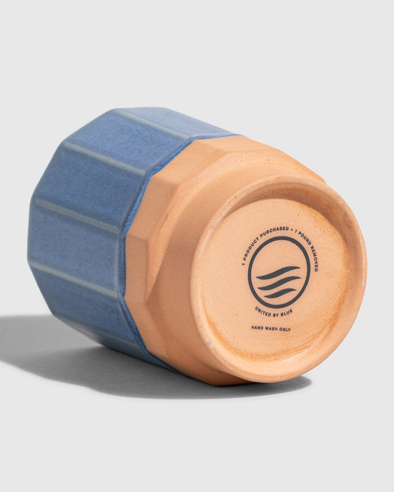 Cobalt 8 oz. Stackable Stoneware Tumbler (Detail): Bottom of blue faceted stoneware tumbler showing brand stamp and care instructions