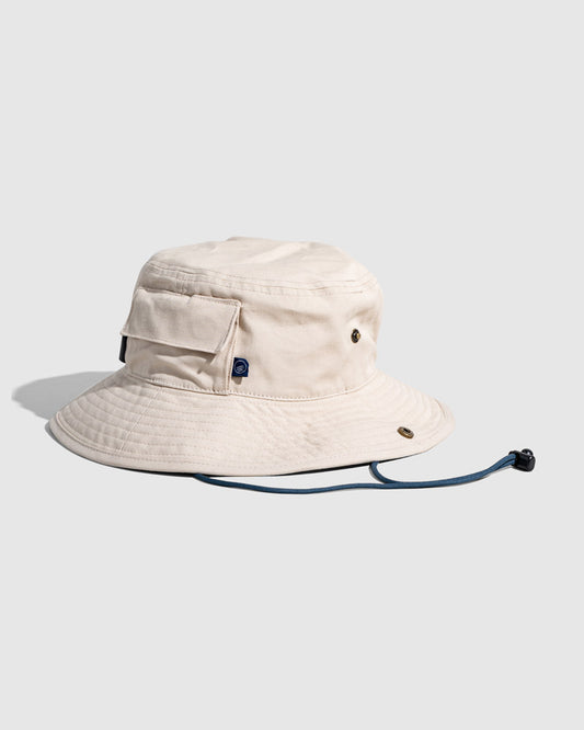 Bone Organic Bucket Stash Hat (Angle): Cream bucket hat with side pocket, brass eyelets, and navy chin cord