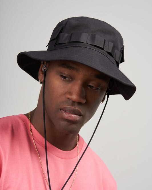 Obsidian Organic Bucket Stash Hat (In-use): Dark bucket hat with webbing band and chin cord, worn by man