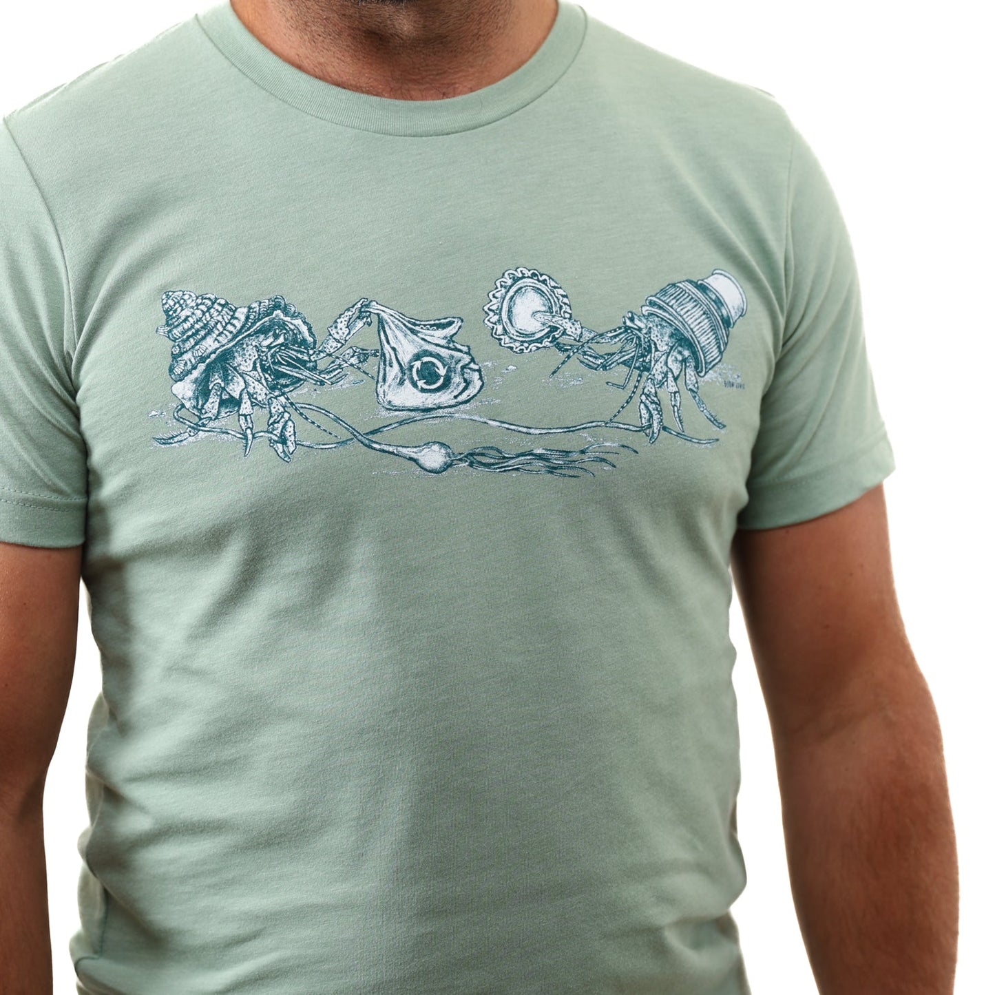 Heather Sage What We Save Graphic Tee - Slow Loris x United By Blue (Detail): Light green tee with hermit crabs carrying trash as makeshift shells