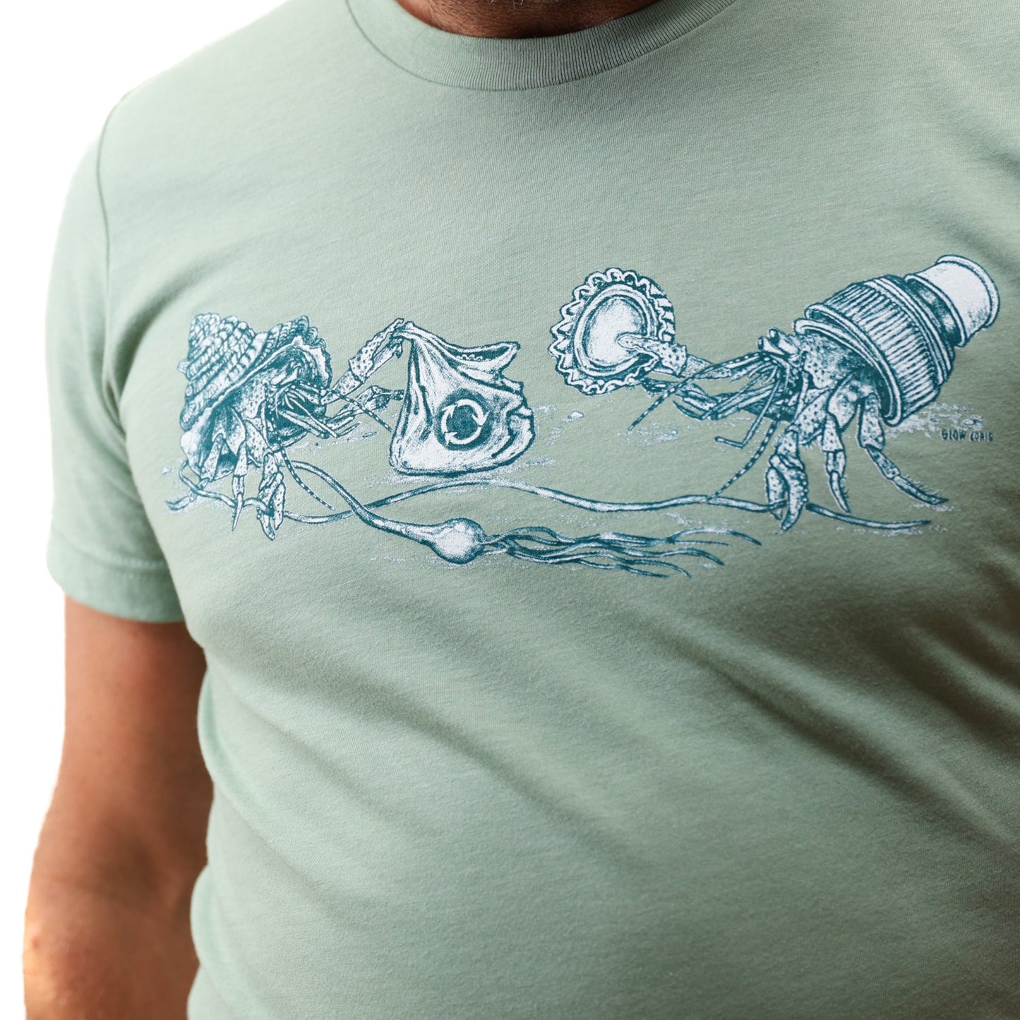 Heather Sage What We Save Graphic Tee - Slow Loris x United By Blue (Detail): Close-up of two hermit crabs exchanging trash items, teal illustration on sage tee