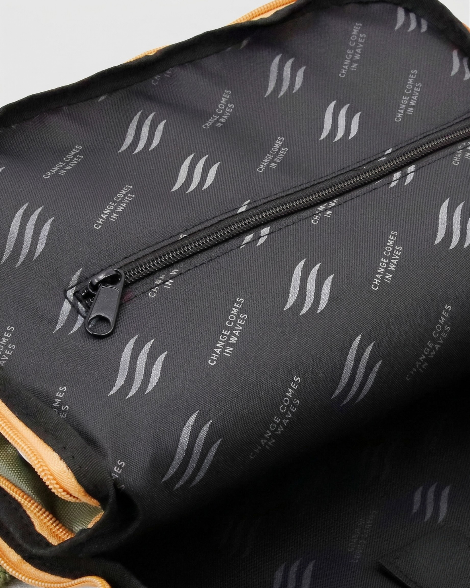 Olive (R)evolution™ 25L Transit Pack (Detail): Black interior lining with wave logos and inner zipper pocket visible