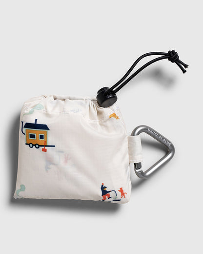 Tusk The Packable Tote (Detail): White pouch with colorful camping print, drawstring closure, and carabiner clip