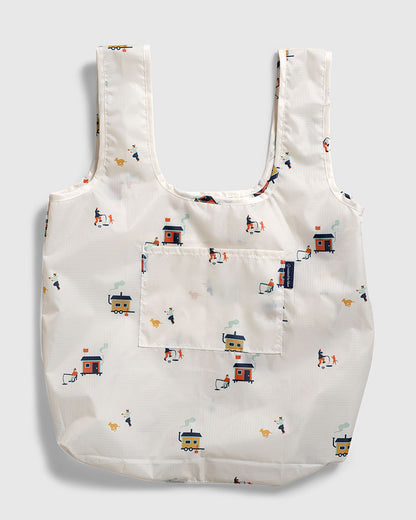 Tusk The Packable Tote (Flat-lay): White tote with small ice fishing hut and dog repeat print, front pocket