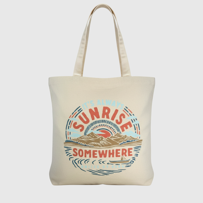 It's Always Sunrise Somewhere My Favorite Daily Tote (Front): Natural canvas tote with circular sunrise mountain scene graphic and shoulder straps