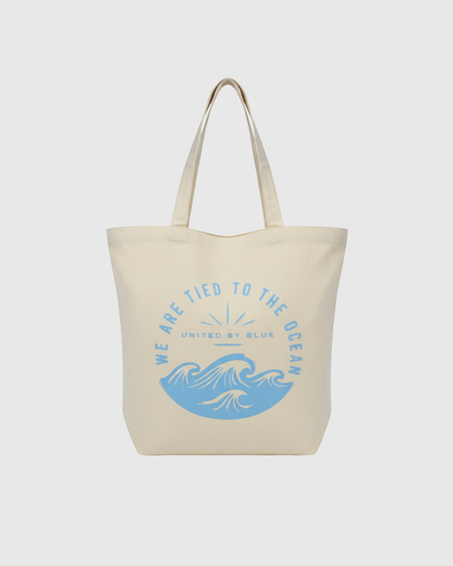 We Are Tied To The Ocean My Favorite Daily Tote (Front): Cream canvas tote with blue ocean waves and arched text graphic