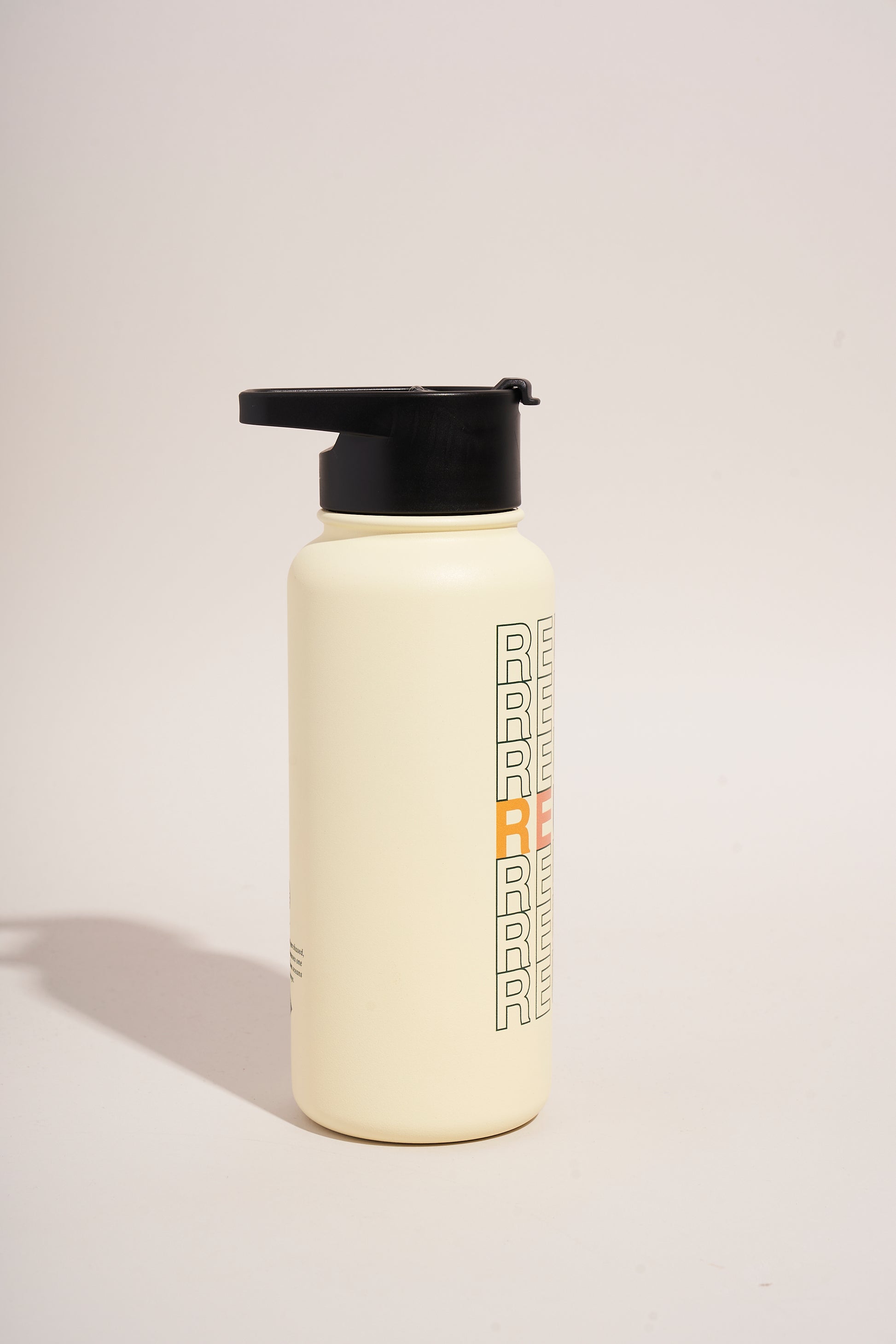 Eggshell - Reuse Bottle - 23 Oz. Insulated Stainless Steel (Angle): Cream stainless steel bottle with black flip lid and repeated letter graphic