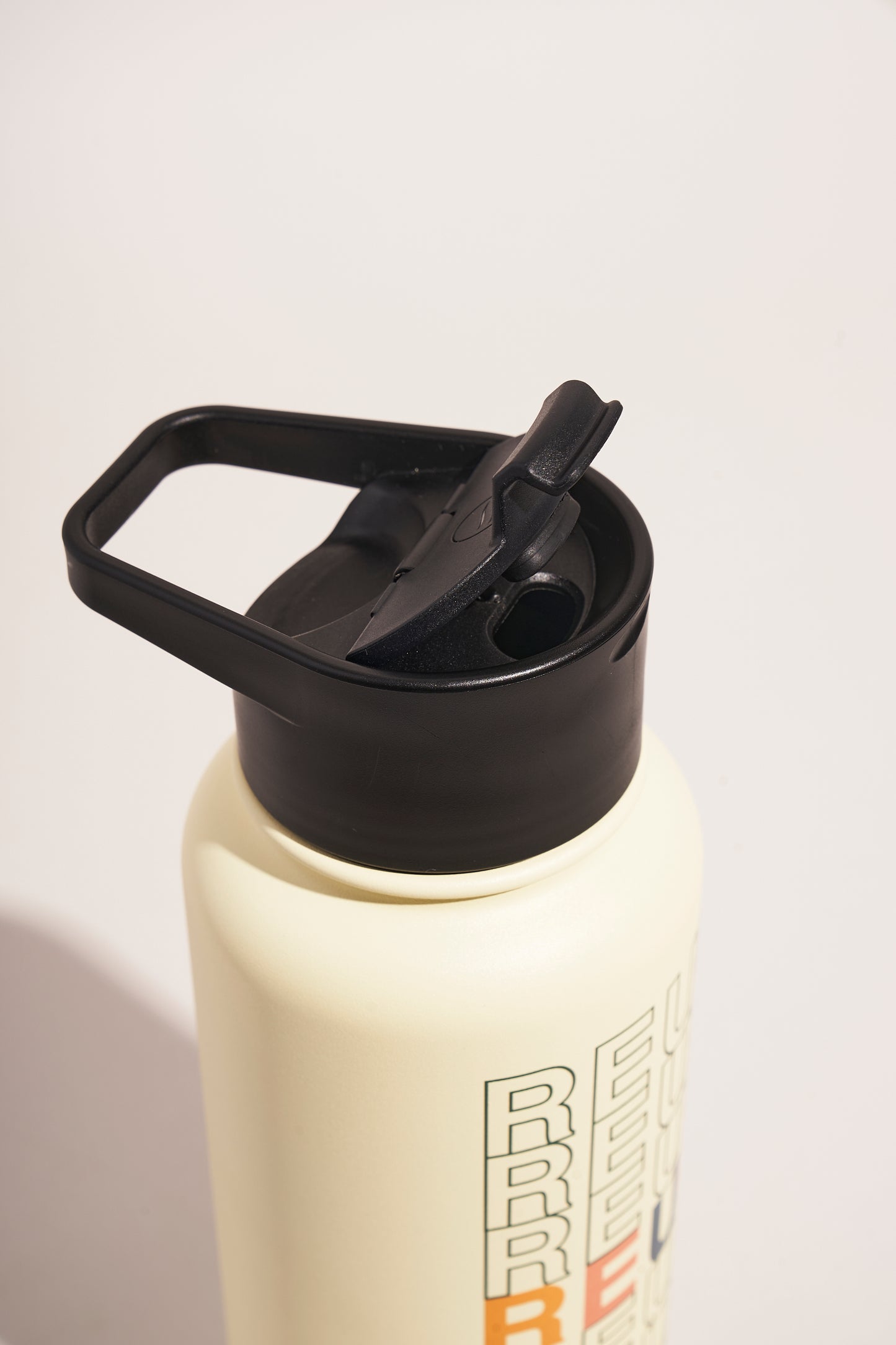 Eggshell - Reuse Bottle - 23 Oz. Insulated Stainless Steel (Detail): Close-up of black flip-top lid with carry handle on cream bottle