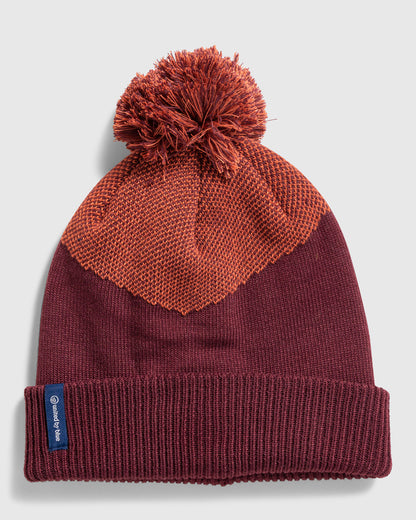 Eggplant Recycled Novelty Pom Beanie (Flat-lay): Deep burgundy knit beanie with orange textured chevron panel and pom-pom top