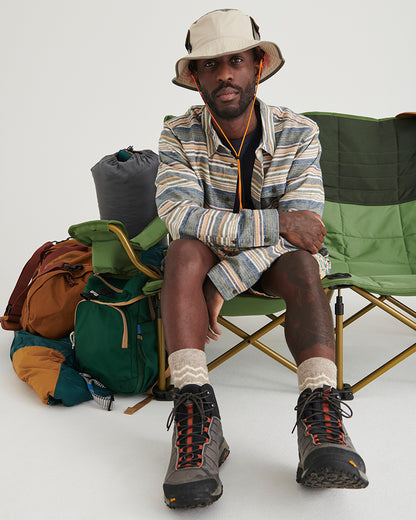 NATURAL / KHAKI UTILITY BUCKET HAT (In-use): Man wearing cream bucket hat seated on green camping chair outdoors