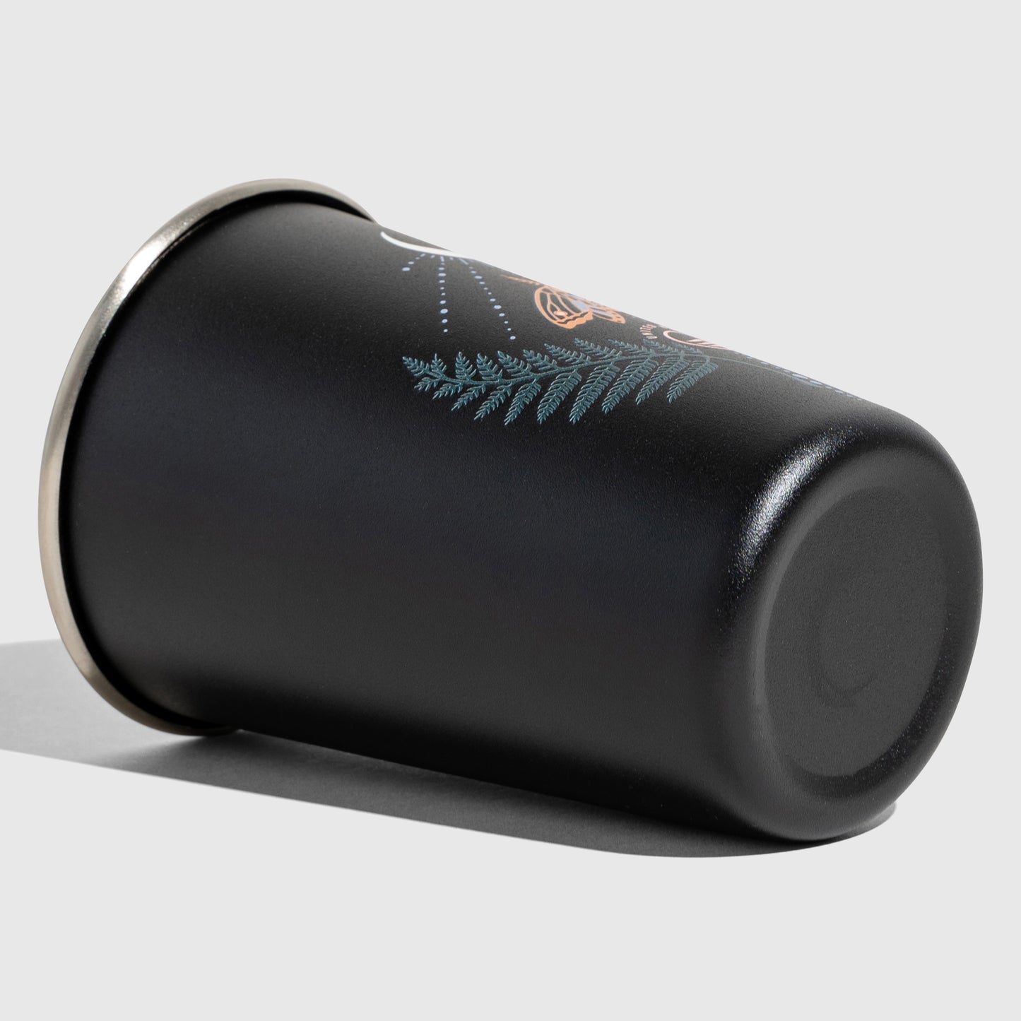 Lunar Moth 16OZ STAINLESS STEEL TUMBLERS (Detail): Black matte tumbler on its side showing teal fern and moth print