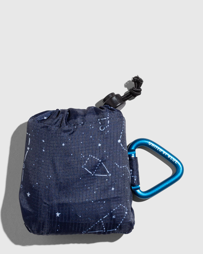 Night Sky The Packable Tote (Angle): Navy constellation-print stuff sack with black toggle closure and blue carabiner clip