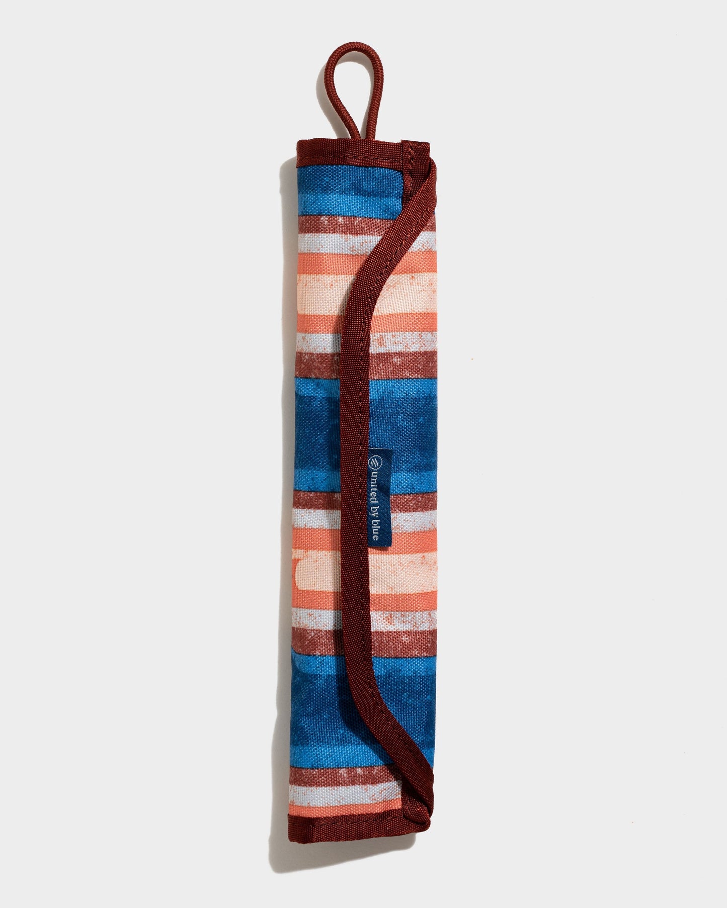 The Straw Kit (Front): Rolled striped pouch with blue, orange, white bands and burgundy trim loop