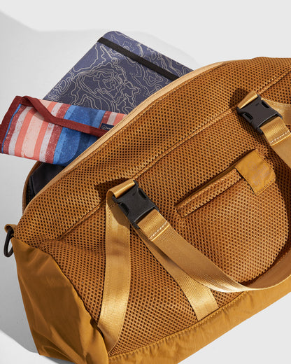 (Re)active™ 16L Mini Duffle (Detail): Tan mesh duffle bag open, showing buckle straps, front pocket, and folded items inside