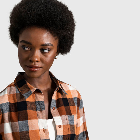 Sunburn The Responsible Flannel - Impact Collection (In-use): Woman wearing open-collar plaid flannel shirt in orange, black, and white