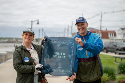 Navy Reusable DIY Cleanup Kit (In-use): Two smiling volunteers hold open a navy blue bandana outdoors