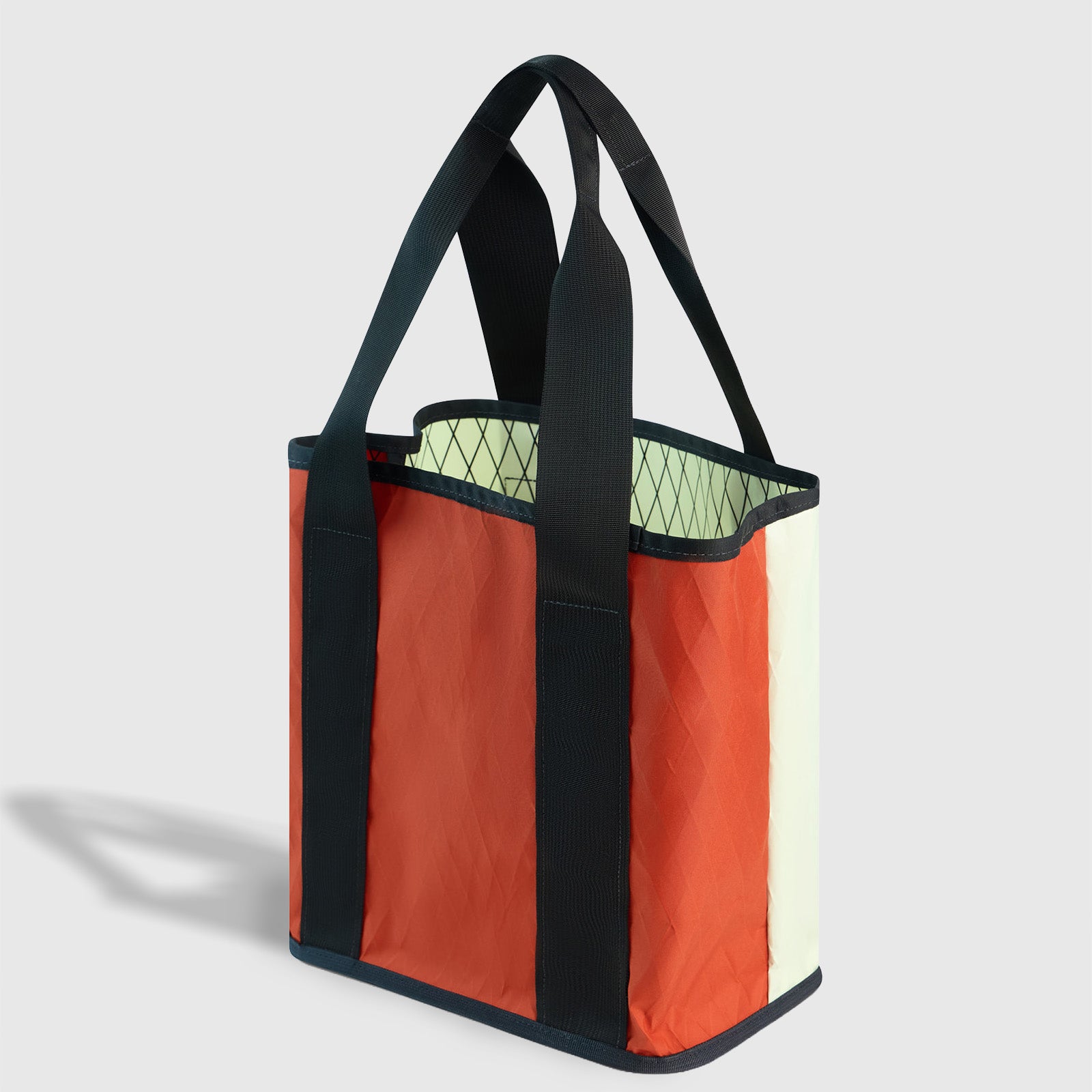 Coyote Coral The Westward Tote (Angle): Open top tote with orange front panel, cream sides, dark straps, green interior
