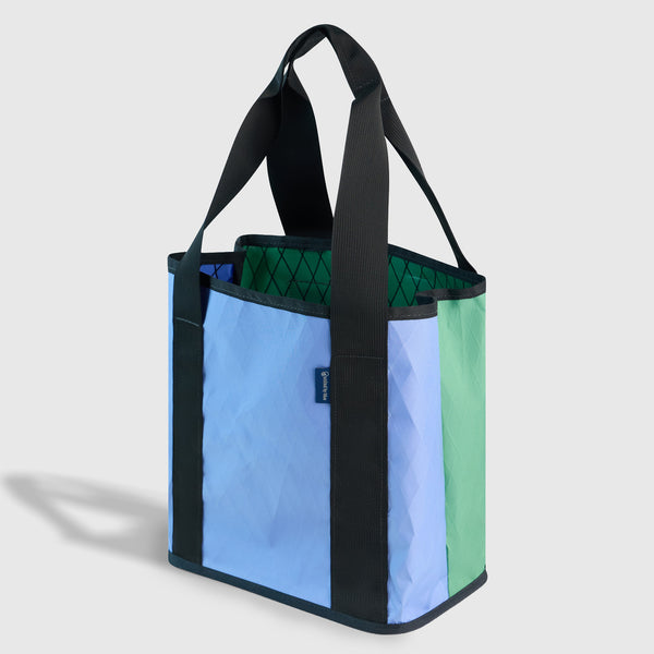 Plum Blue The Westward Tote (Angle): Blue and green tote with black handles, straps, and quilted interior