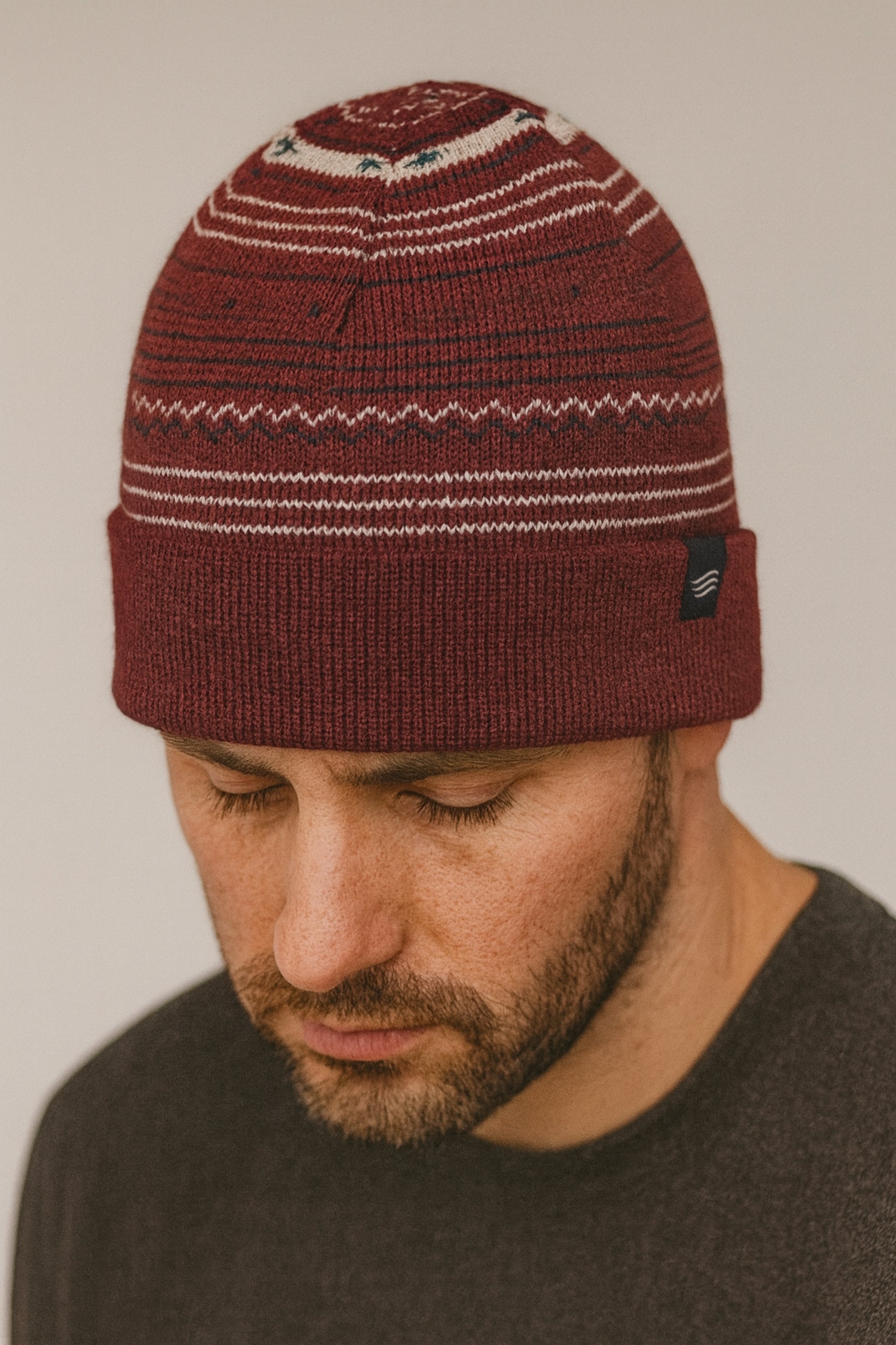 Burgundy Multi Merino Wool Modern Fair Isle Knit Beanie (In-use): Bearded man wearing dark red fair isle knit beanie with white stripe details