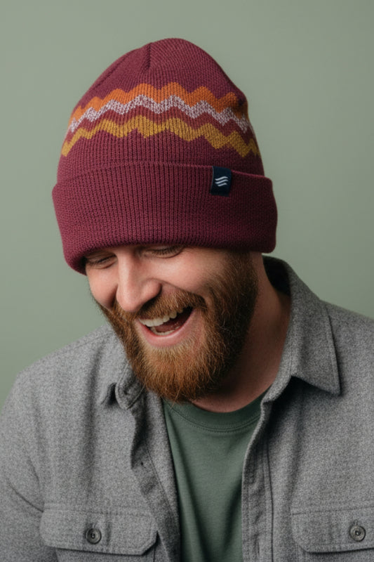 Burgundy Merino Wool Mountain Scape Knit Beanie (In-use): Laughing bearded man wearing burgundy zigzag-patterned knit beanie with cuffed brim