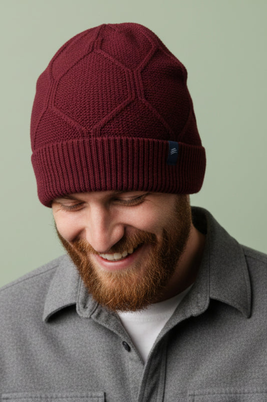 Berry Yak Cable Knit Beanie (In-use): Smiling bearded man wearing dark red cable-knit cuffed beanie, looking down