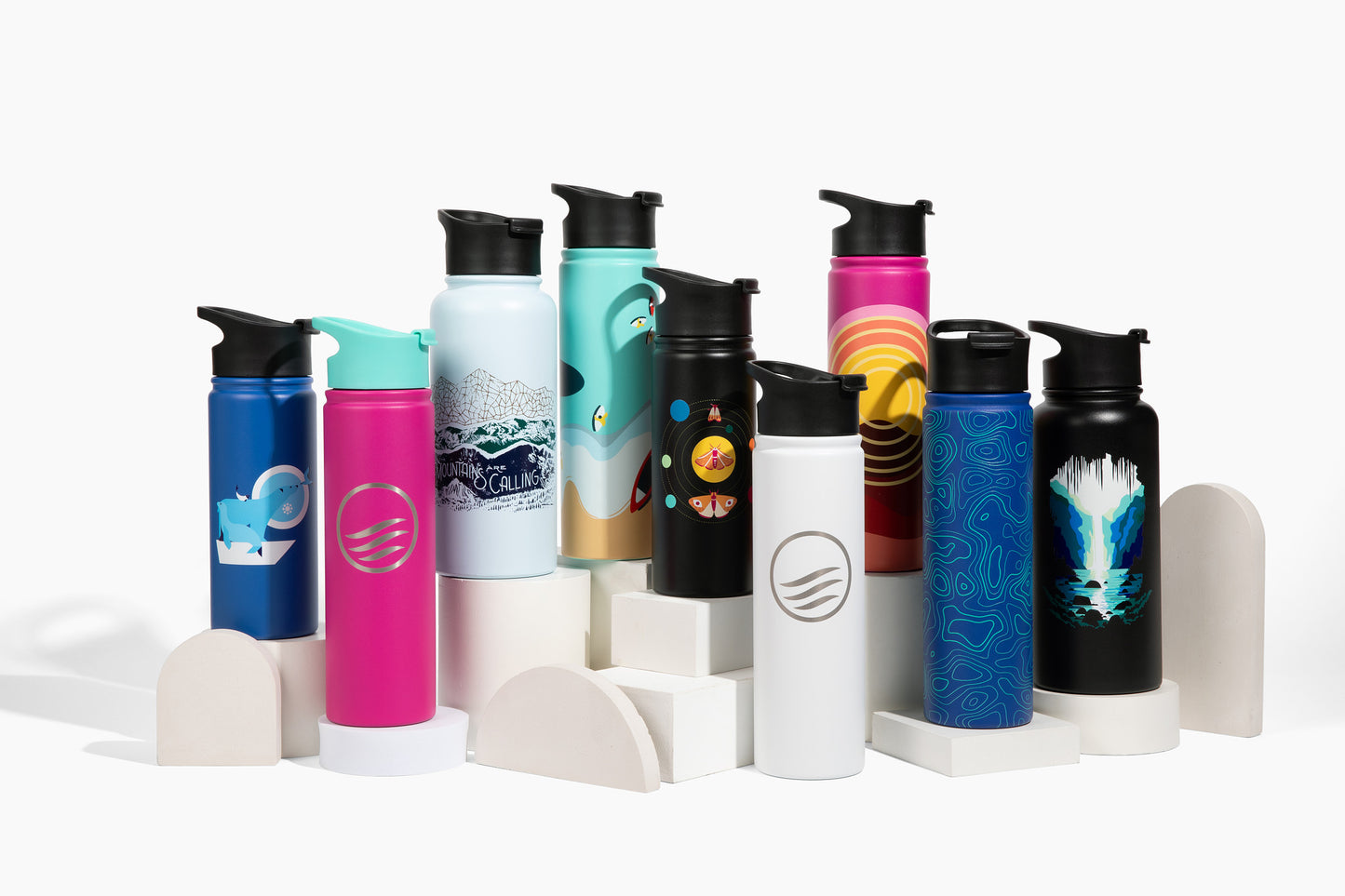 Bottle - 18 Oz. Insulated Stainless Steel (Lifestyle): Collection of colorful insulated bottles with black flip-top lids on white pedestals