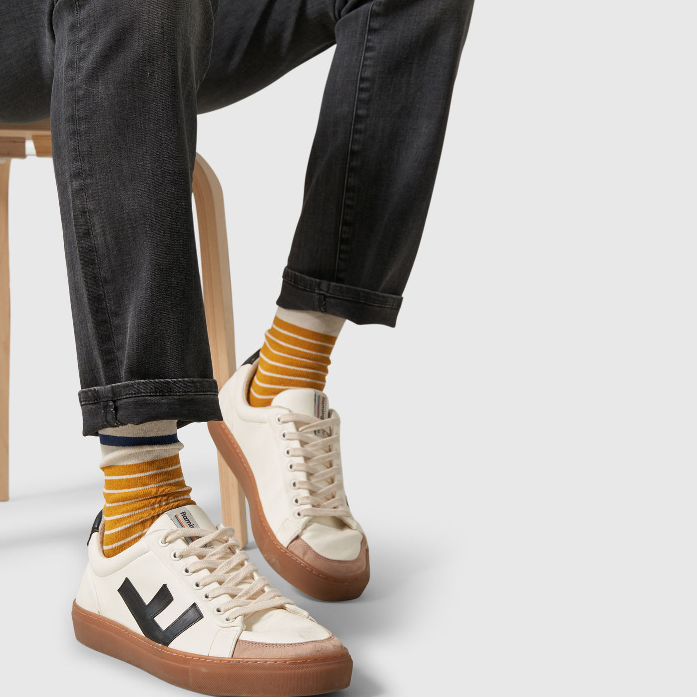 Wood Thrush IMPACT COLLECTION - Hemp Blend Socks (In-use): Mustard yellow striped crew socks worn with white sneakers, legs crossed on stool