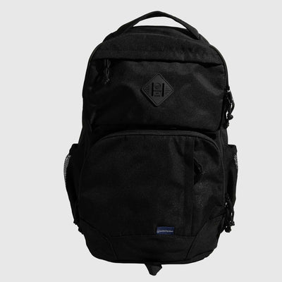 Black (R)evolution™ 25L Transit Pack (Front): All-black backpack with diamond logo patch, multiple zippered compartments, mesh side pockets