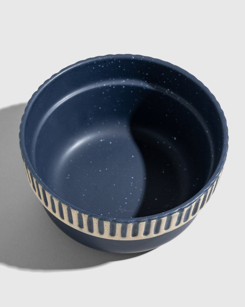 Slate Stoneware Stackable Bowl (Angle): Dark blue speckled bowl with cream vertical stripe band and scalloped rim