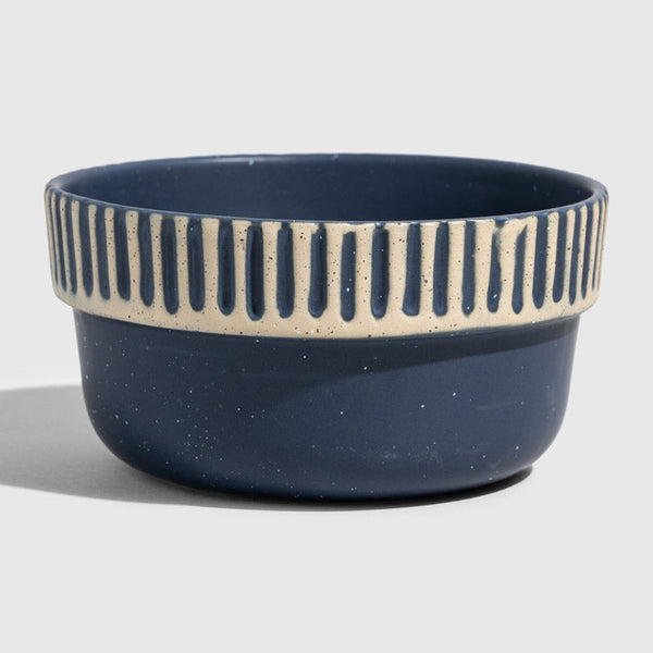 Slate Stoneware Stackable Bowl (Angle): Round ceramic bowl, navy blue with cream carved vertical stripe band near rim