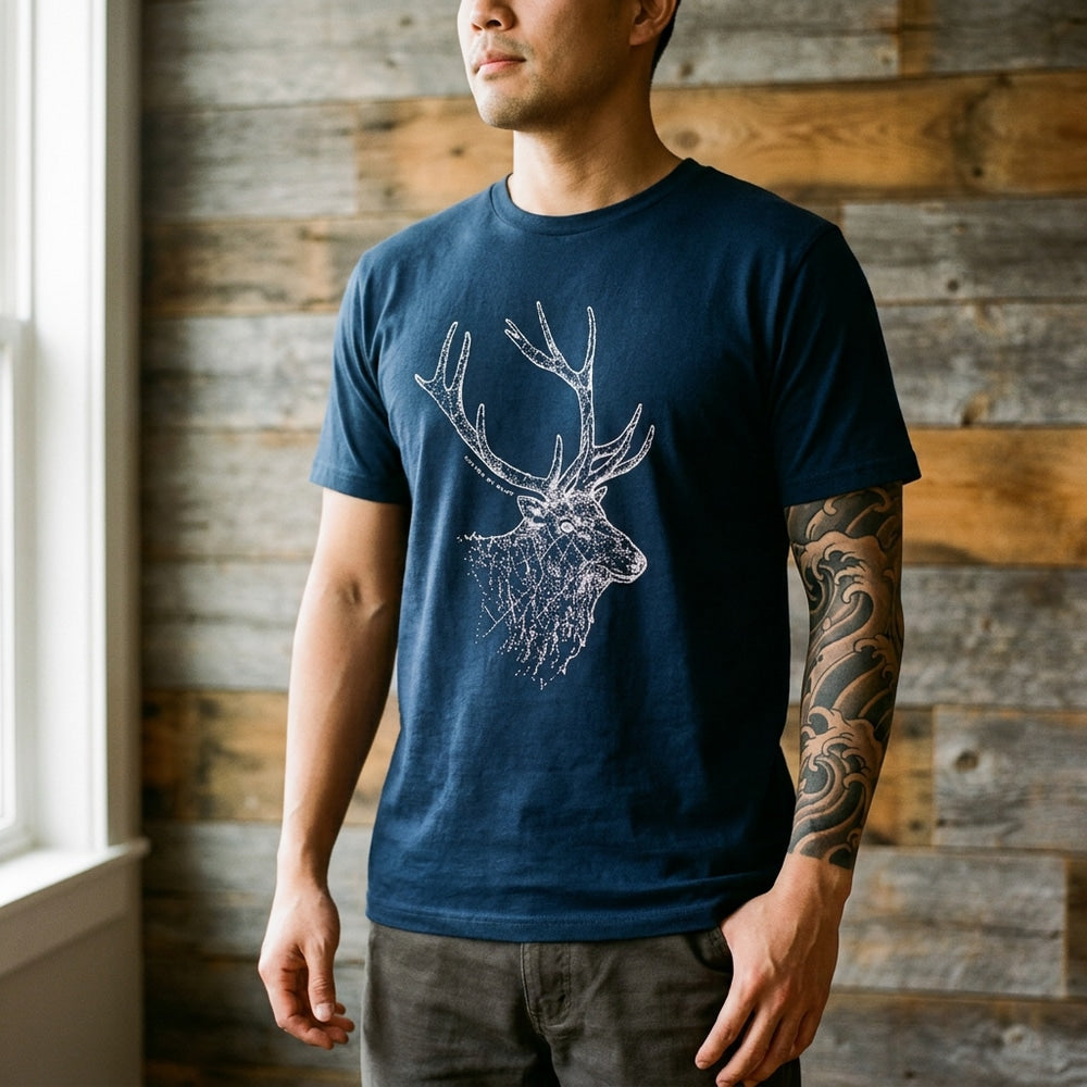 navy Unisex Graphic Tee in 100% Organic Cotton - The Elk (In-use): Man wearing dark blue tee with white elk graphic, wave sleeve tattoo visible