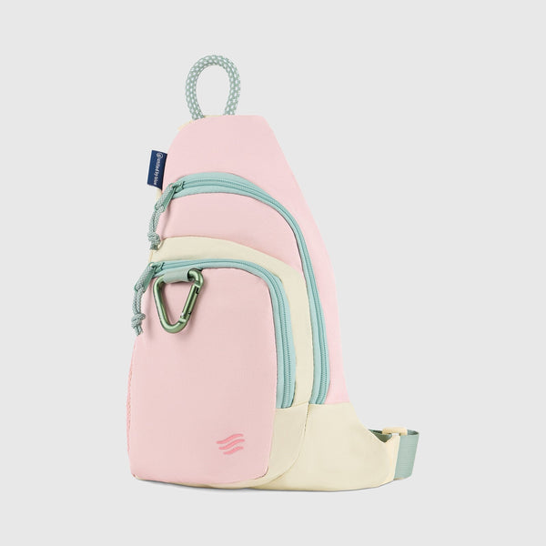 Pink Multi (R)evolution Sling Pack (Angle): Pink sling pack with sage zippers, cream base, and green carabiner