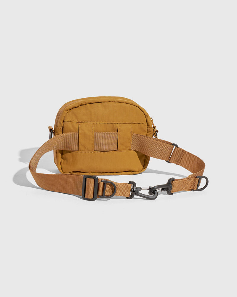 Smoky Ochre (Re)active™ 2L Convertible Crossbody (Angle): Golden-tan small crossbody bag, back view, webbing strap with buckle clasp