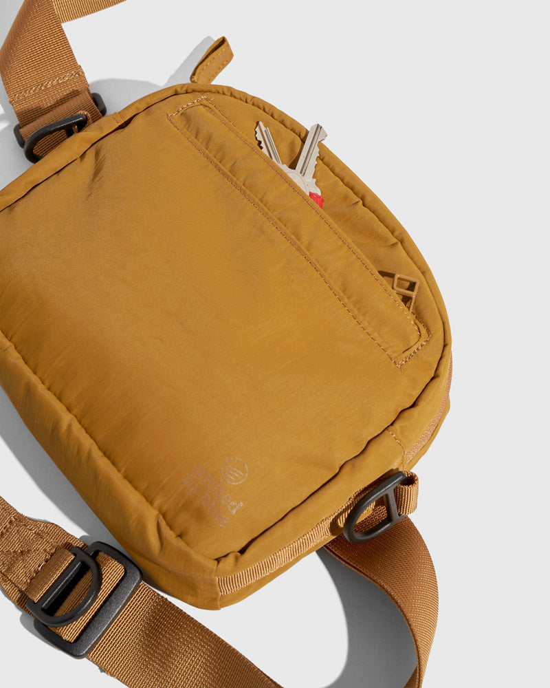 Smoky Ochre (Re)active™ 2L Convertible Crossbody (Detail): Golden-tan crossbody back panel with open slip pocket holding keys