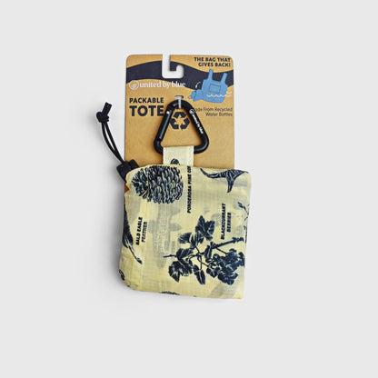 Grizzly The Packable Tote (Front): Yellow packable tote with navy botanical print, folded into pouch with carabiner clip
