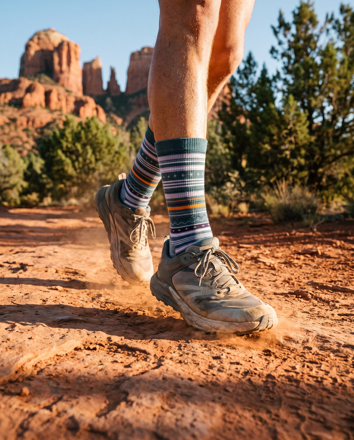 Trail runner on red dirt below Arizona red rock, wearing the teal Merino Wool Trail Crew Sock