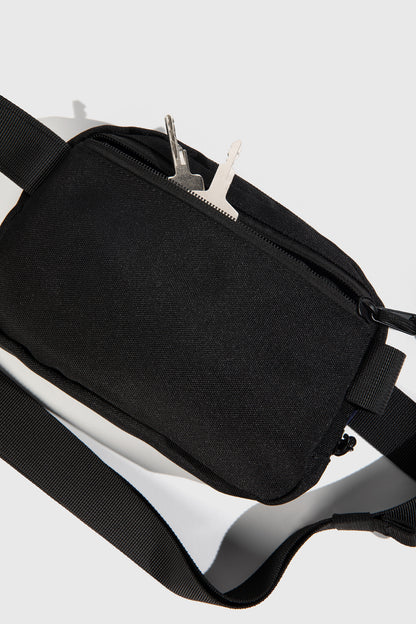 Black (Re)volution™ 1L Go-Anywhere Bag (Detail): Black canvas bag with front zipper pocket and silver keys tucked inside