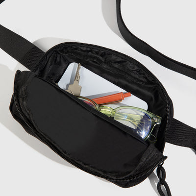 Black (Re)volution™ 1L Go-Anywhere Bag (Detail): Black fanny pack open, showing glasses, keys, card, and pen inside